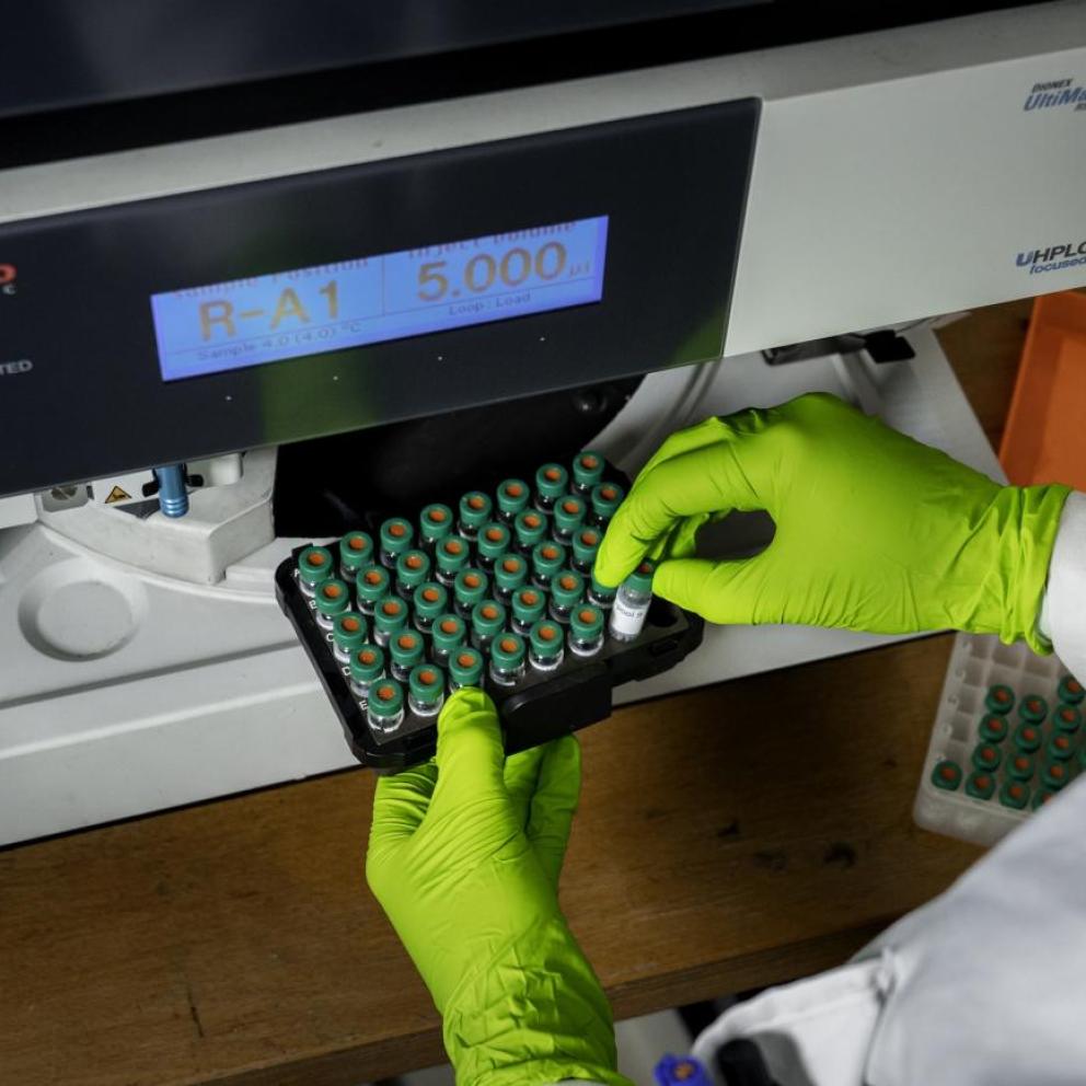 Scientifique plaçant des produits en tubes dans un appareil de mesure