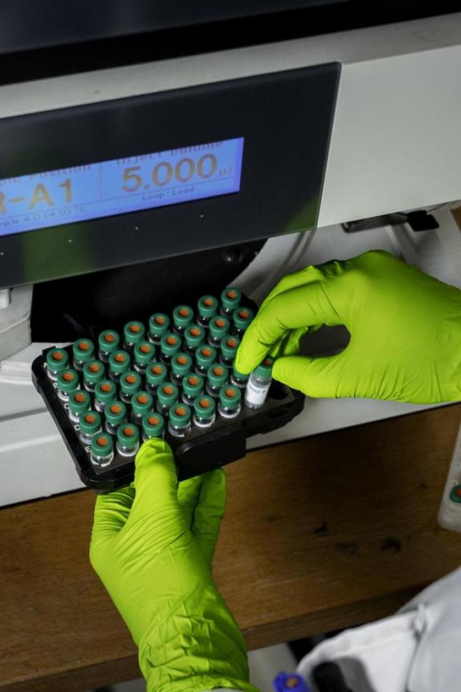 Scientifique plaçant des produits en tubes dans un appareil de mesure