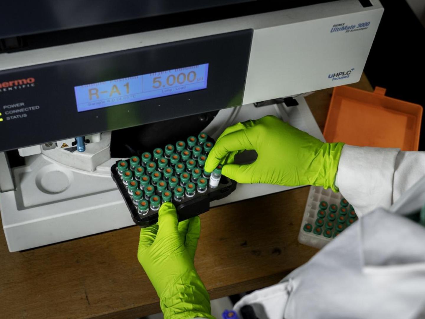 Scientifique plaçant des produits en tubes dans un appareil de mesure